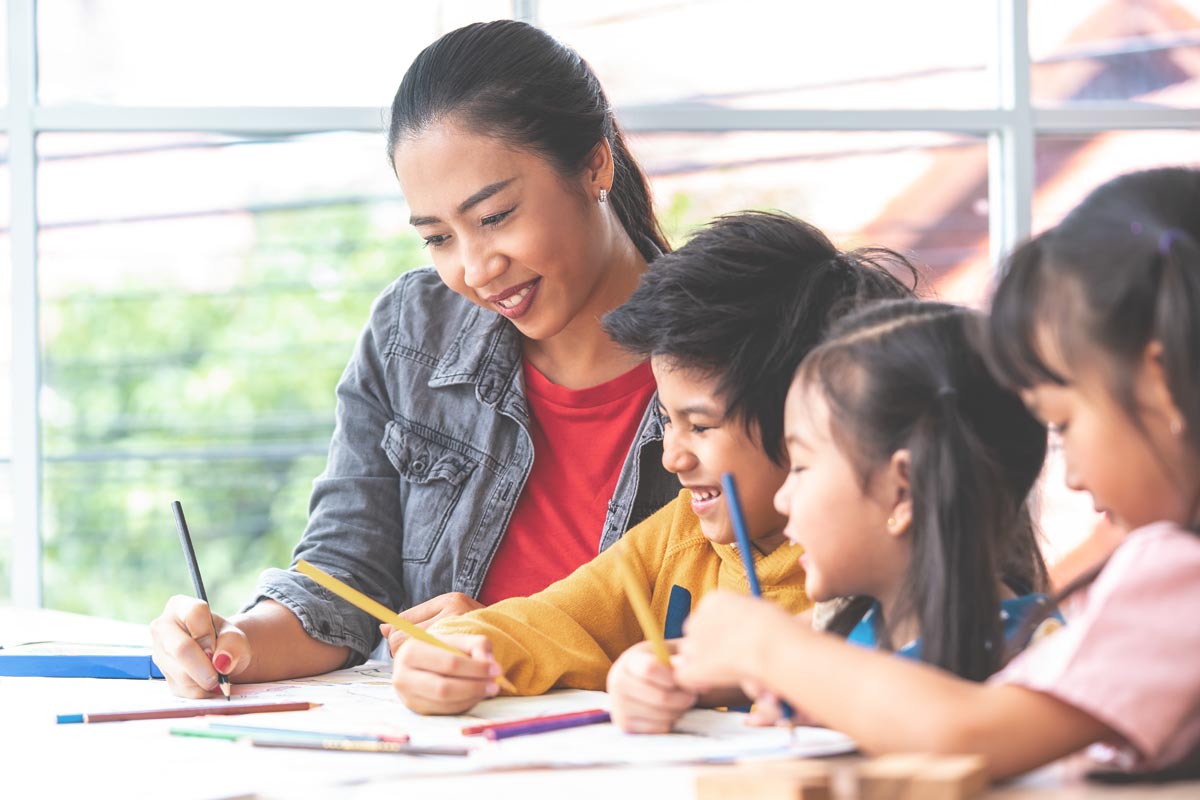 Children and teacher in class room, coloring