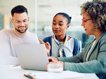 Young multiracial couple and their health care navigator using laptop during meeting in office