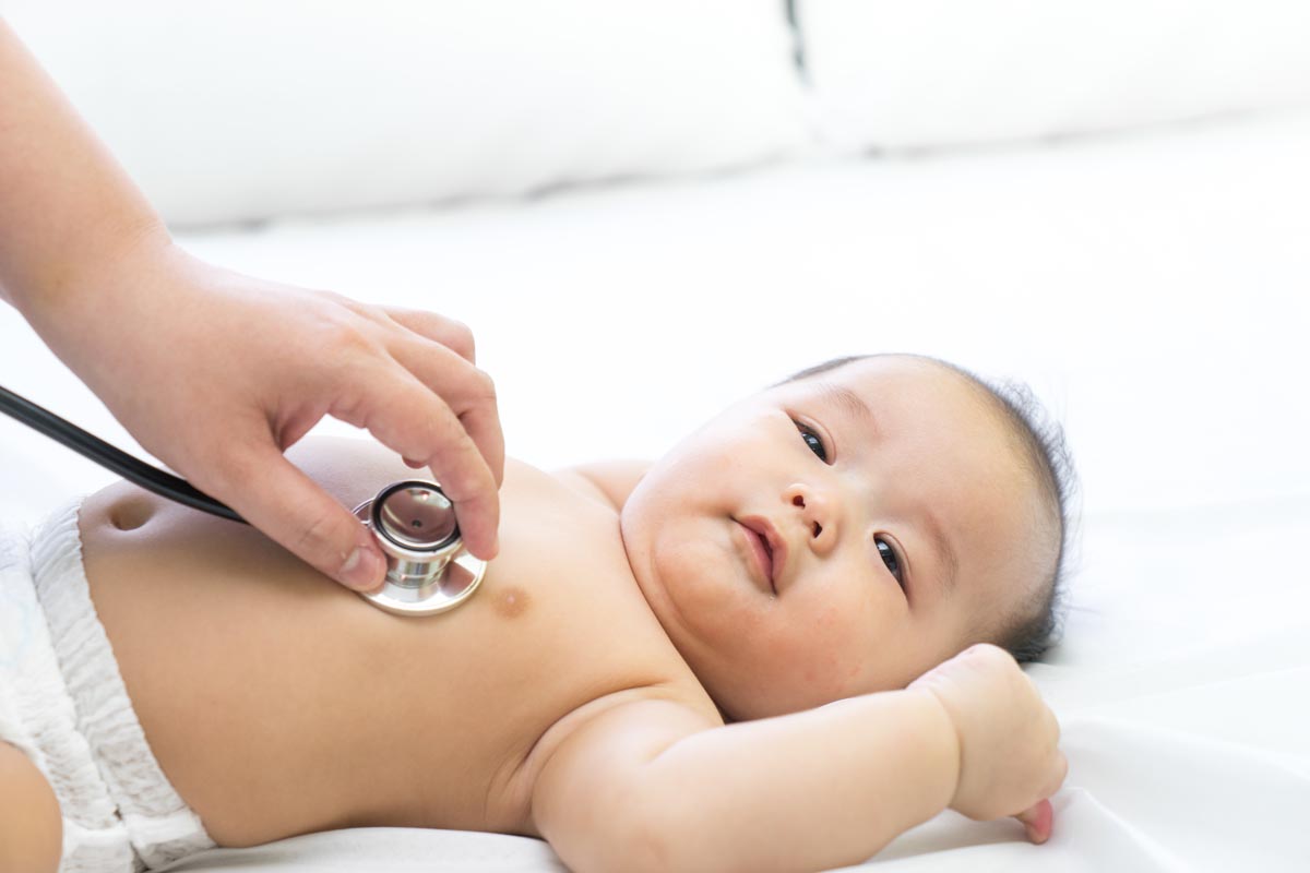 Infant with stethoscope against heart