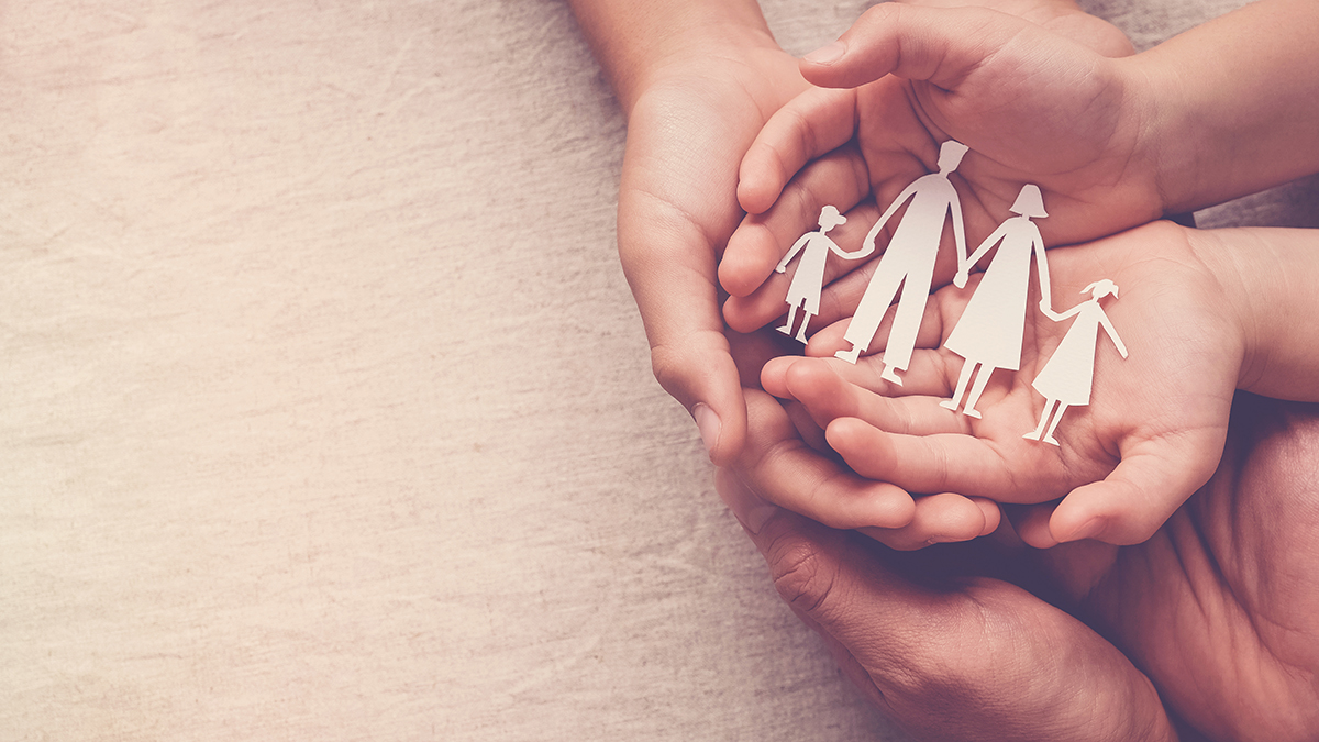 three generations of hands holding paper cutout of a family