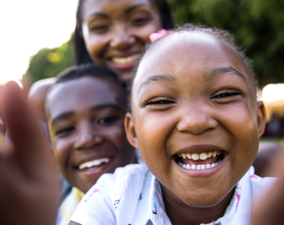 child smiling in foreground friend and parent in background