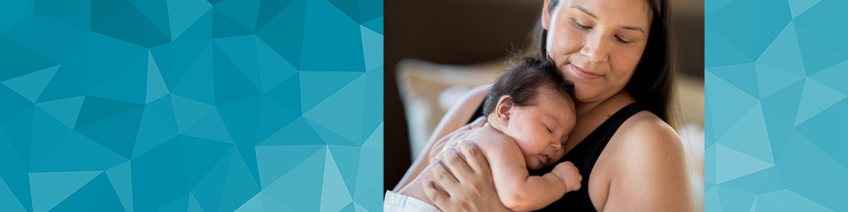 Smiling mother cradling newborn infant to her chest.